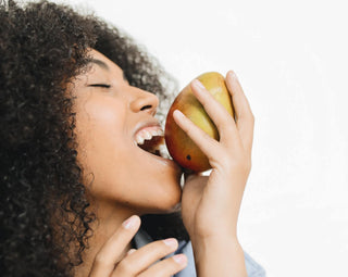 A woman is eating a fruit to have healthier skin