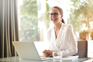 Laughing businesswoman working in office with laptop.