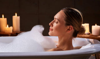 a woman is taking a bath with candles