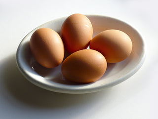 Four eggs on the white, round plate naturally coloured for Easter. This image is related to self care during Easter time.