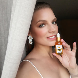 A woman is holding natural facial oil in her hand.