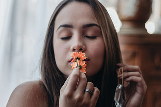 A woman is enjoying the scent of a flower.